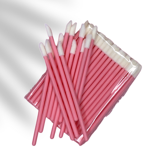 Disposable lip applicators pink handle and white tip stacked on top of each other.  