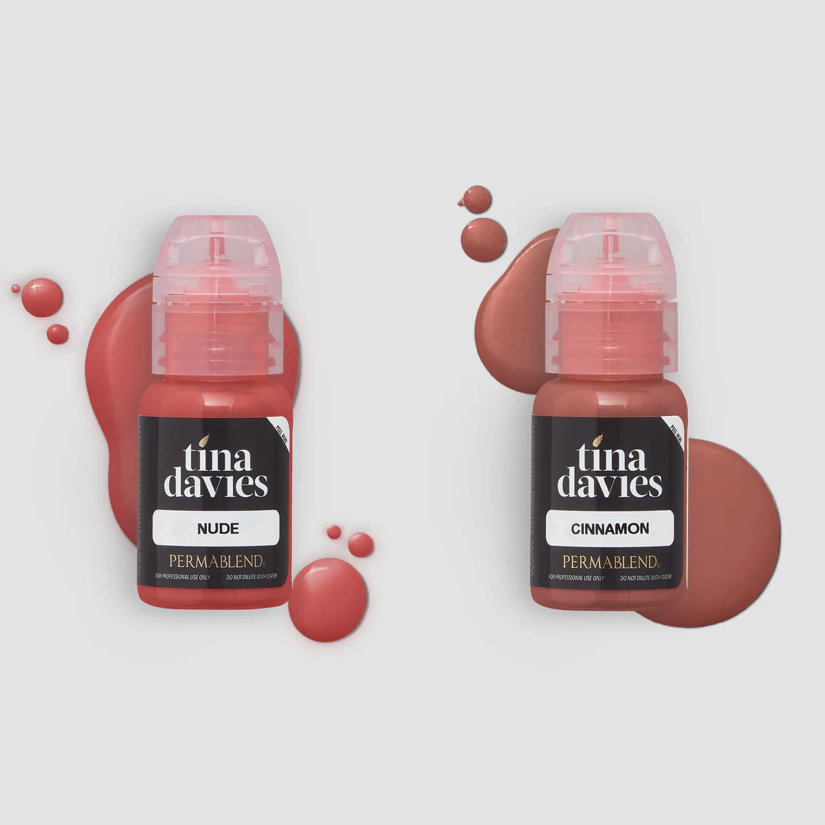Two tina davies lip pigments side by side in clear bottles so you can see the vibrant pigment colour through them.  Pigment also spilt in drops behind bottle for effect. 