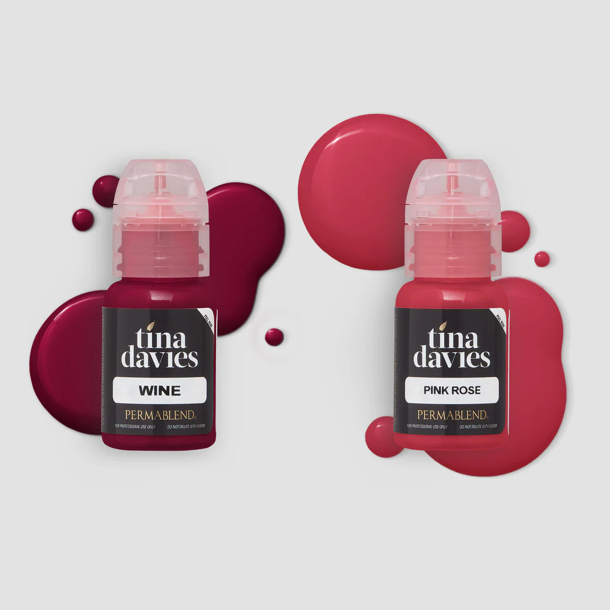 Two tina davies lip pigments side by side in clear bottles so you can see the vibrant pigment colour through them. Pigment also spilt in drops behind bottle for effect.